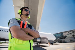 Staying positive. Low angle portrait of serene man standing at airport and looking away with half-smile