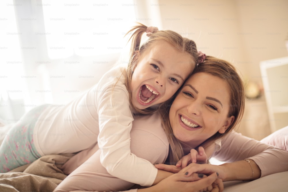 Laughter and love. Mother and daughter in bed.