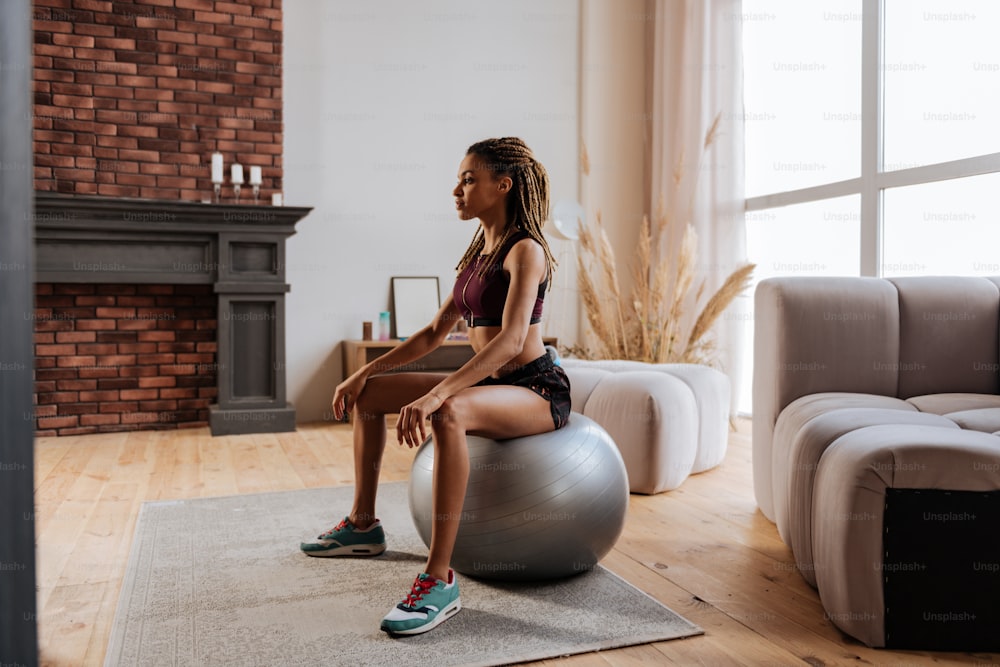 Exercising on ball. Young slim and fit businesswoman exercising on fitness ball at home in the morning