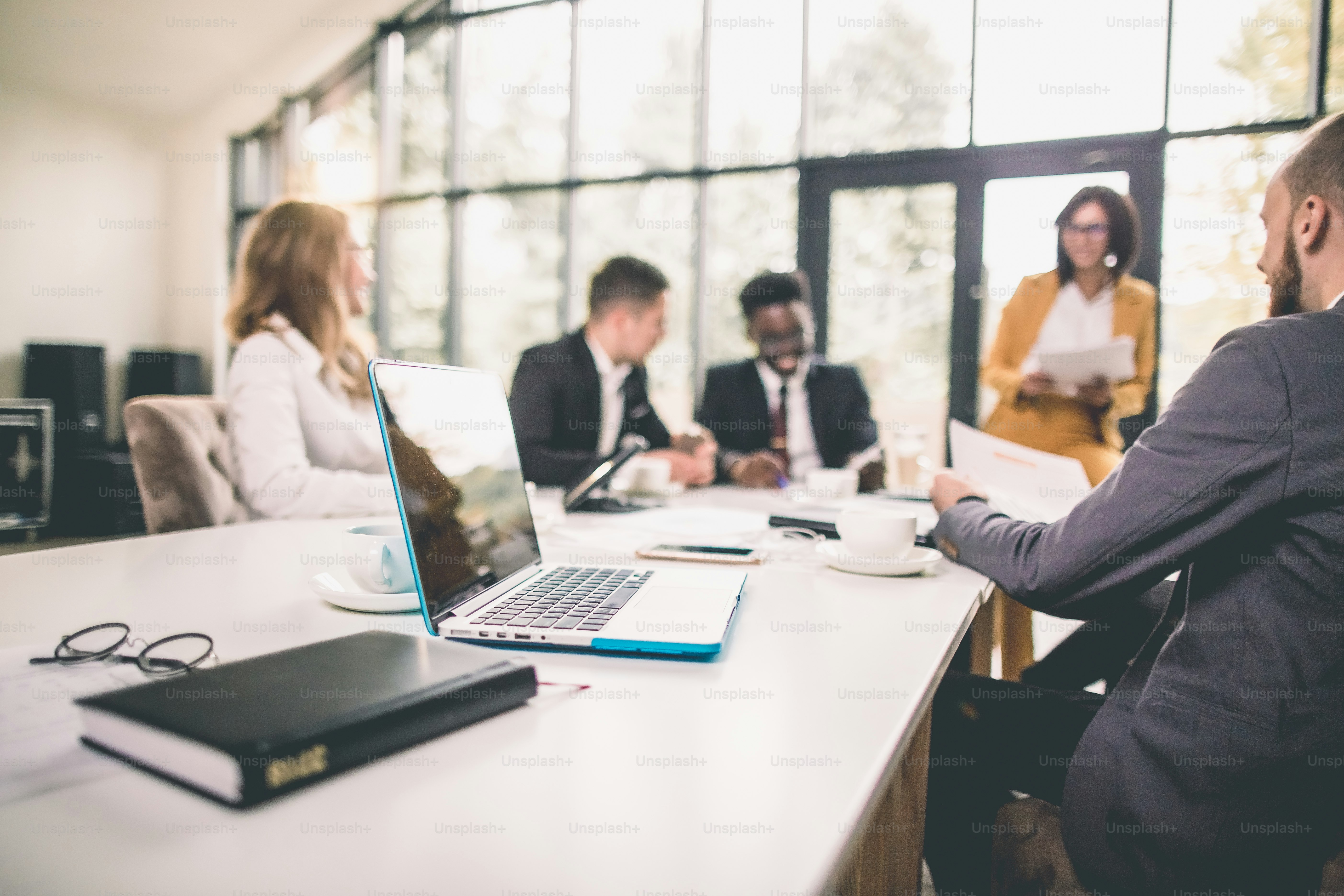 Chef d’équipe et propriétaire d’entreprise à succès dirigeant une réunion d’affaires informelle à l’interne. Homme d’affaires travaillant sur un ordinateur portable au premier plan. Concept d’entreprise et d’entrepreneuriat.