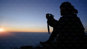 Fotógrafo Tirando Fotos na Vista da Montanha com silhueta nascer do sol.