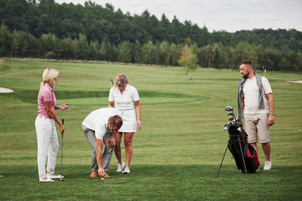 Un gruppo di amici alla moda sul campo da golf impara a giocare a un nuovo gioco.