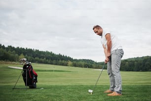 Profi-Golfspieler zielt mit Schläger auf den Platz. Männlicher Golfer auf Putting Green kurz davor, den Hit zu nehmen.