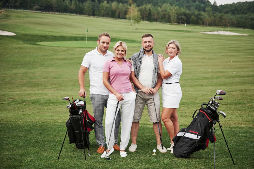 Group of stylish friends on the golf course learn to play a new game. The team is going to rest after the match.