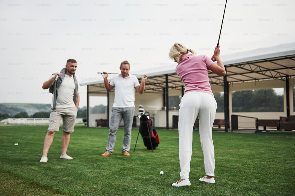 Un grupo de amigos con estilo en el campo de golf aprende a jugar un nuevo juego.