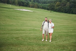Couple sportif jouant au golf sur un terrain de golf, ils se tiennent jusqu’au trou suivant.
