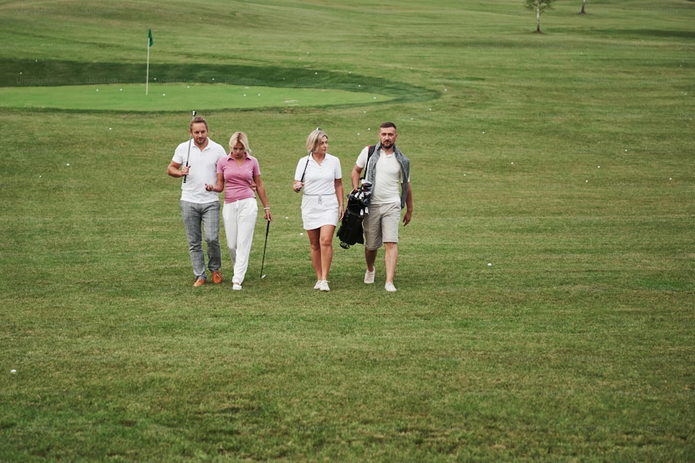 Group of stylish friends on the golf course learn to play a new game. The team is going to rest after the match.