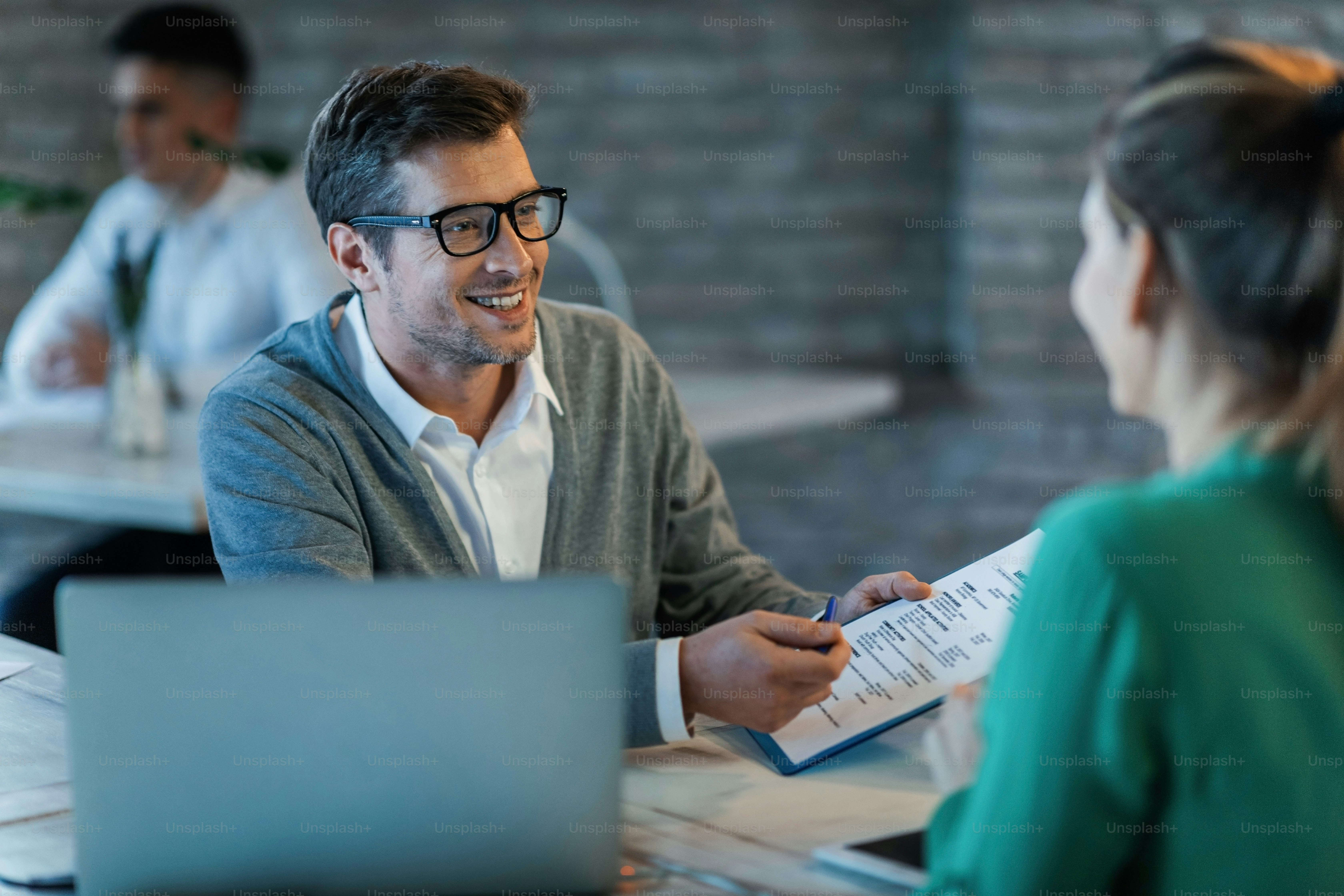 Happy businessman talking to his colleague while going through financial reports in the office