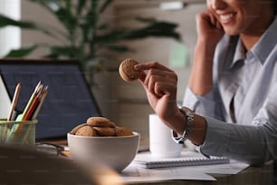 Close up of businesswoman eating cookies on a break in her office.