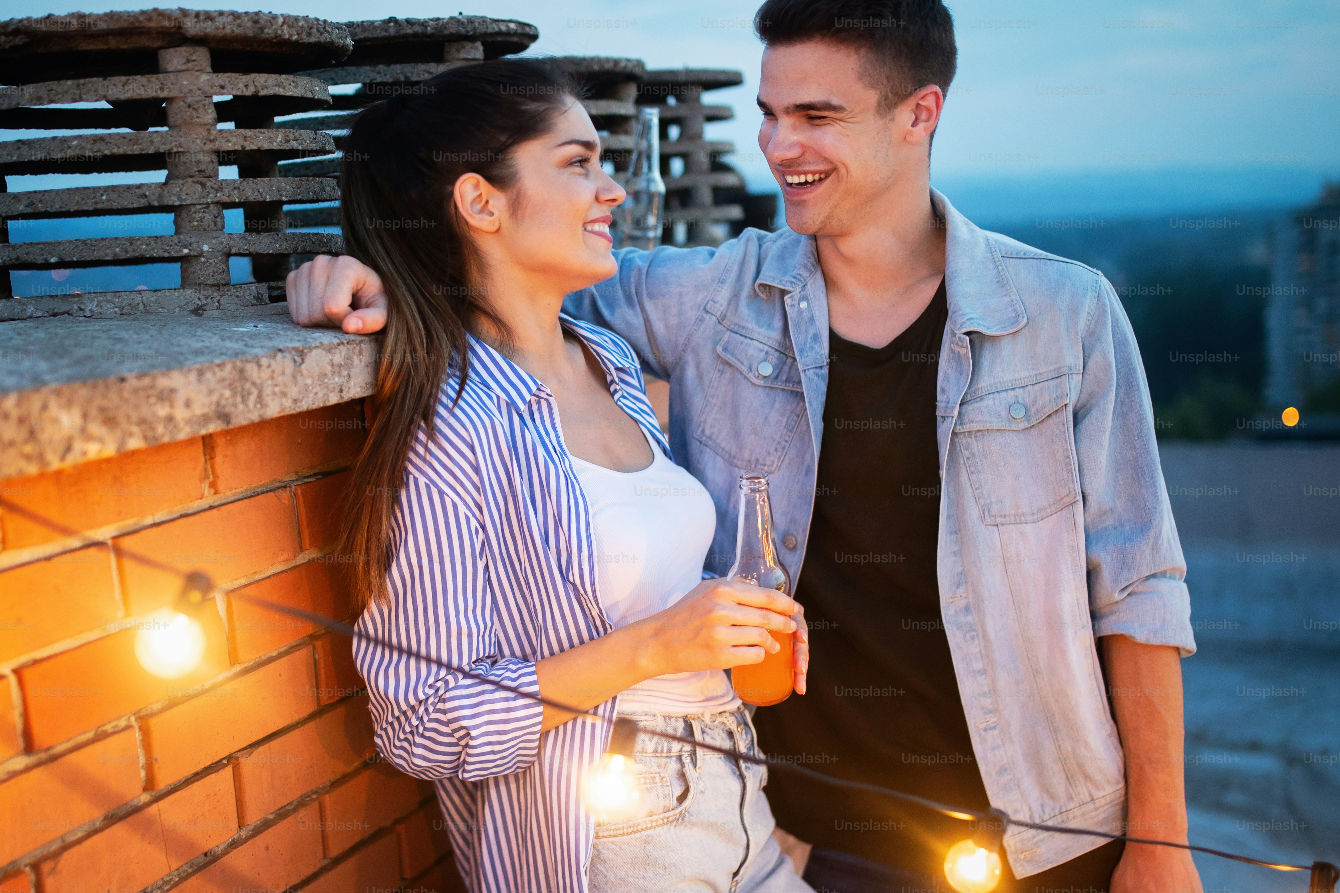 Happy young couple enjoying drinks and balcony party.