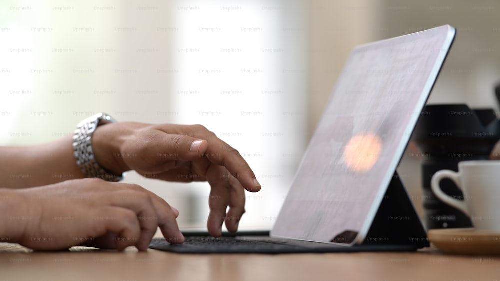Mãos masculinas que trabalham no computador do tablet pc no escritório moderno e brilhante do coworking