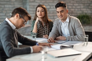 Smiling couple having a meeting with financial advisor in the office.