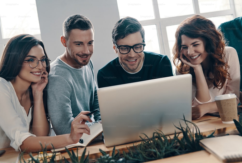 Group of young modern people in smart casual wear using modern technologies while working in the creative office