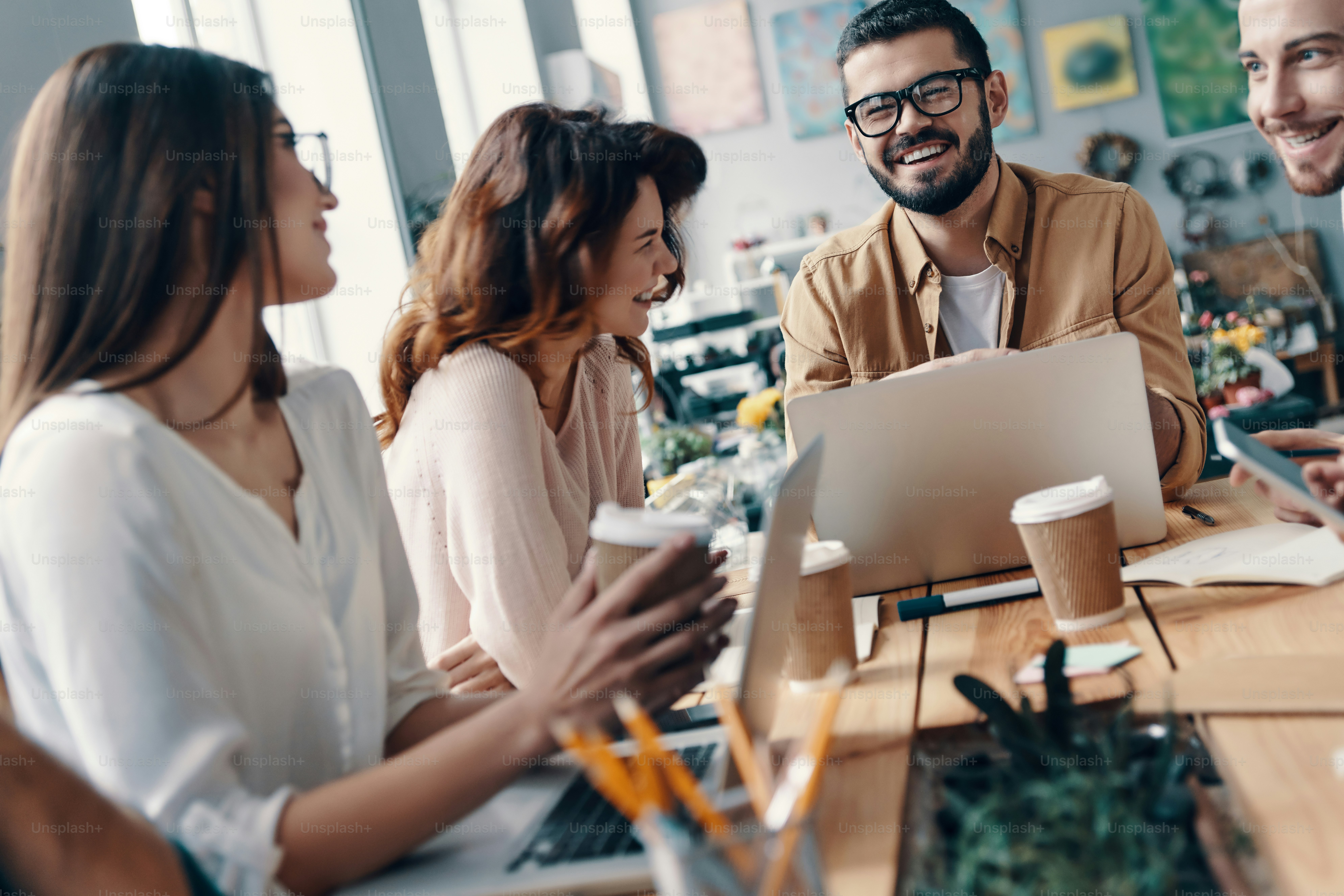 Group of young modern people in smart casual wear discussing something and smiling while working in the creative office