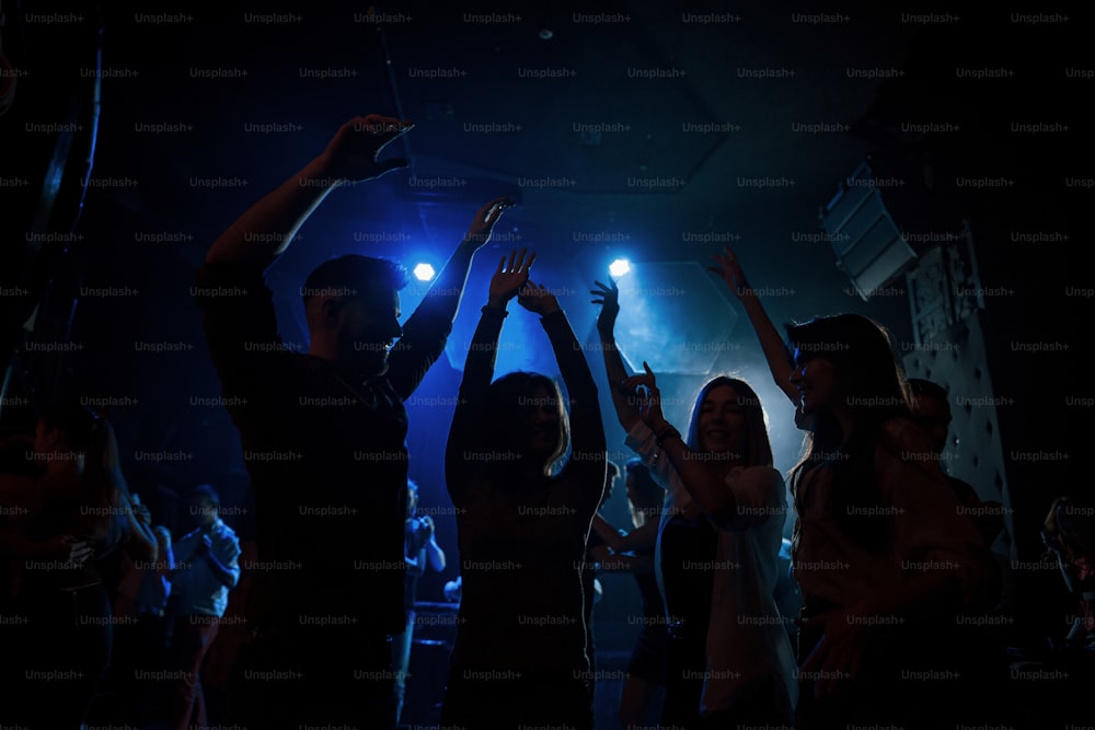Energische Menge. Gruppe von Menschen, die gerne im Nachtclub mit schöner Beleuchtung tanzen.