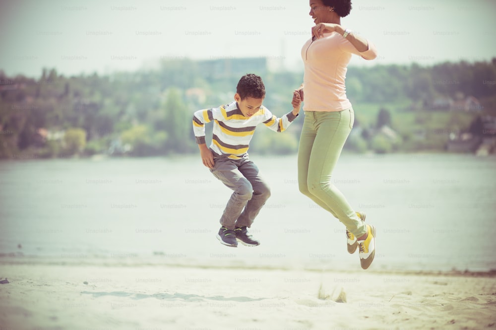 Jump and be happy. Mother and son on the beach.