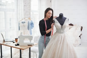 Stellt sich vor, wie es auf der Braut sitzen wird. Modedesignerin arbeitet in der Werkstatt an den neuen Kleidern.