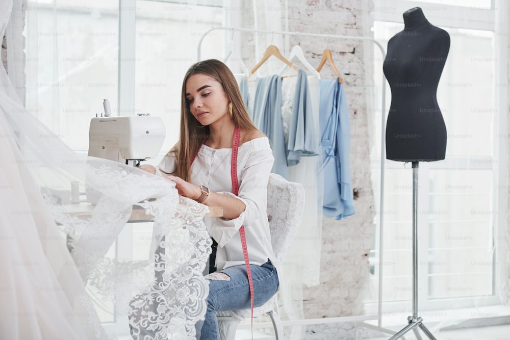 El proceso de costura del vestido. Una diseñadora de moda trabaja en la ropa nueva en el taller.