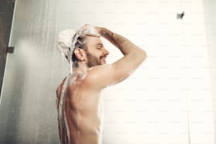 Handsome smiling guy lathers his body.Smiling male turning away from camera