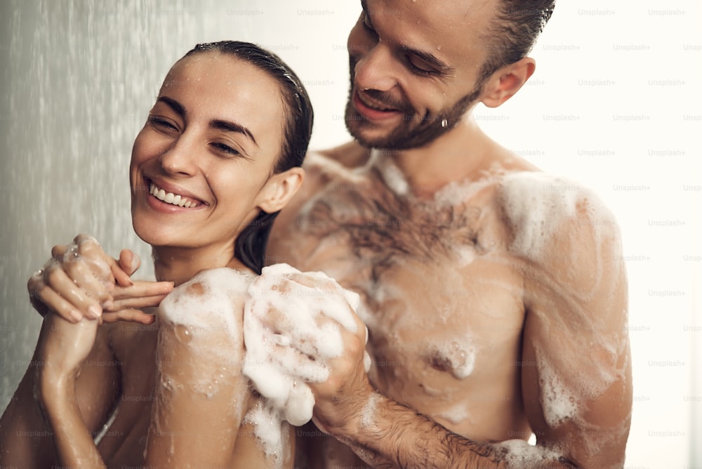 Schönes Paar Frau mit nassen Haaren und gut bemuskeltem Körper beim Duschen. Paar verbringt Zeit miteinander