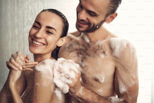 Lovely pair of woman with wet hair and well-muscled body having shower. Couple spending time together
