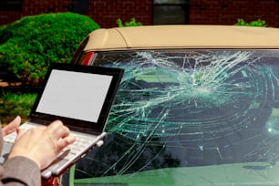 Agente de seguros preenchendo formulário de reivindicação de seguro no laptop após acidente do para-brisa