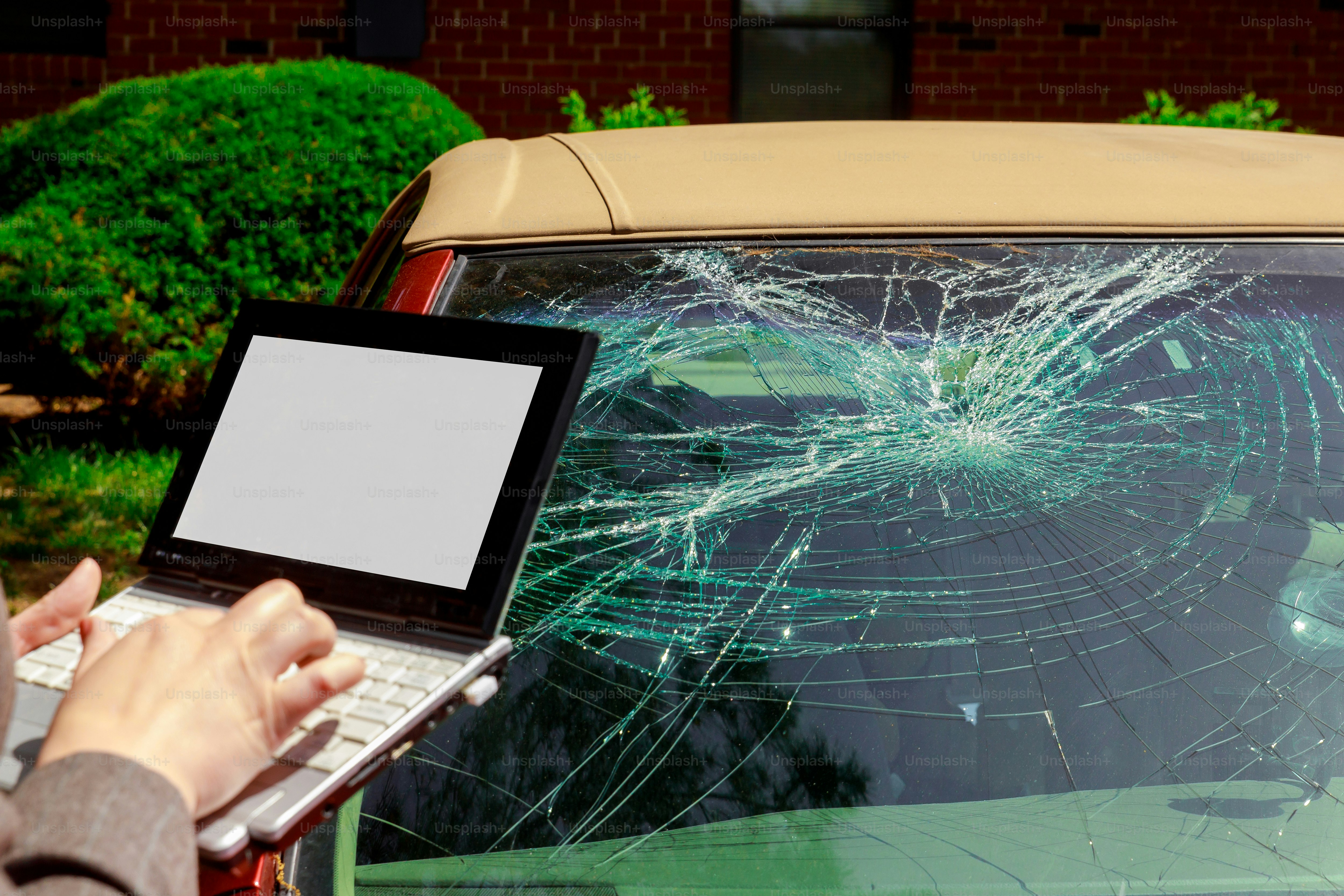 Insurance agent filling Insurance claim form on laptop after windshield crash