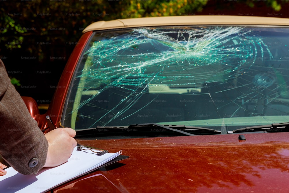 Insurance agent estimates the cost of damaged windshield after car accident,