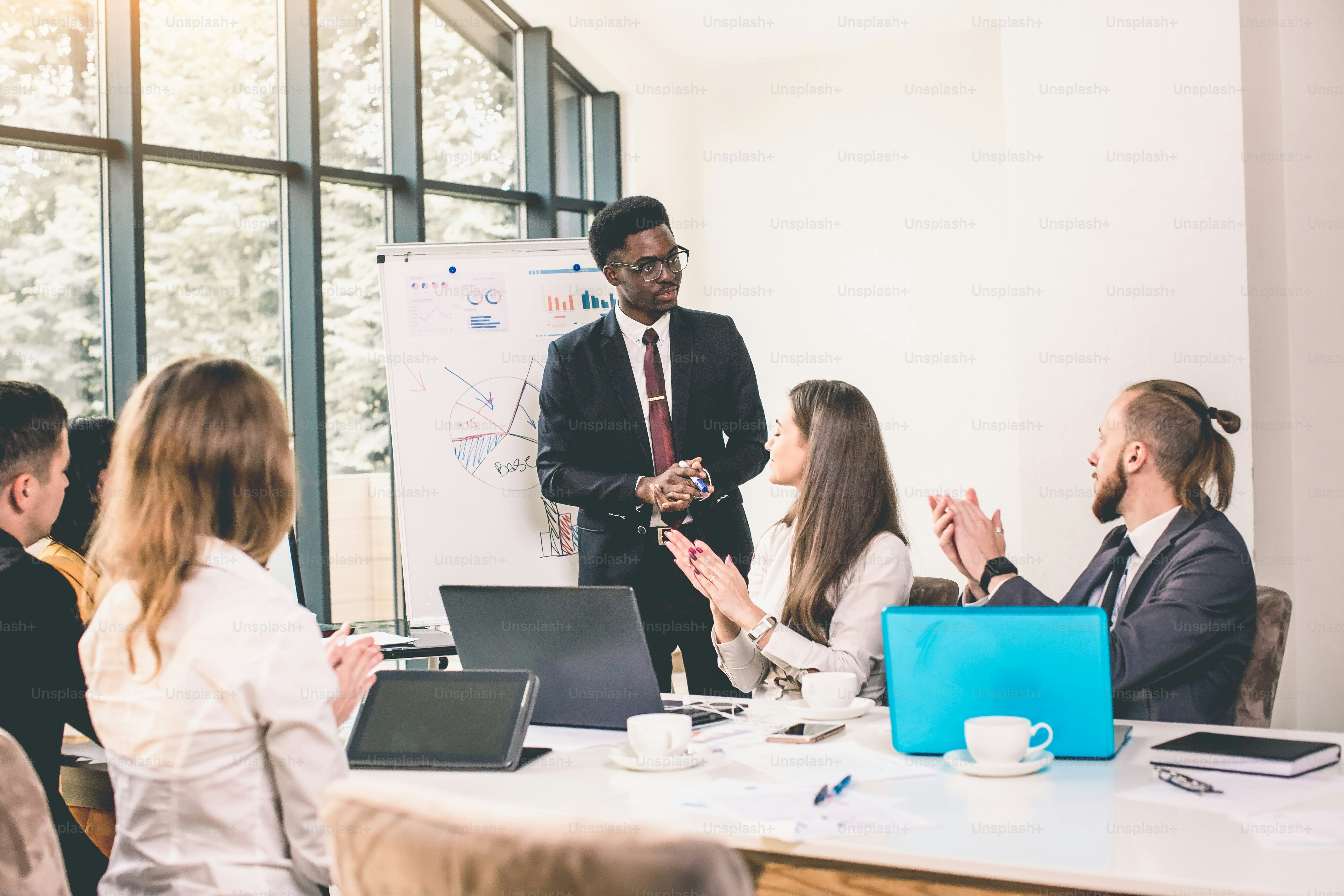 L’équipe d’affaires parle à un candidat afro-américain à l’entretien de travail au bureau. jeune homme afro-américain debout et fait un rapport près du tableau blanc.