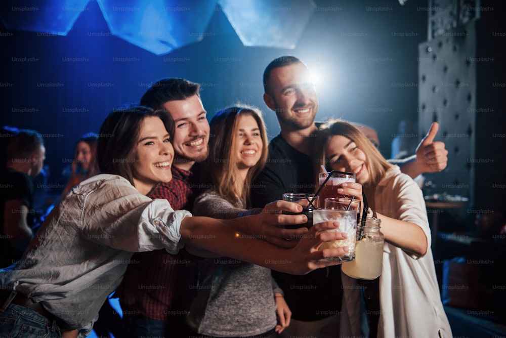 Cheerful mood. Group of young friends smiling and making a toast in the nightclub.
