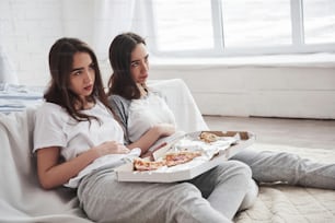 Suffers from overeating. Twins have full stomach with pizza. Nice bedroom at daytime.