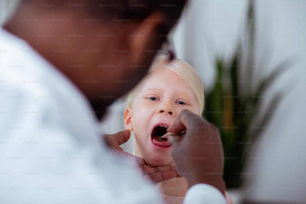 Menina abrindo a boca. Close up da menina loira abrindo a boca ao chegar ao médico com forte dor de garganta