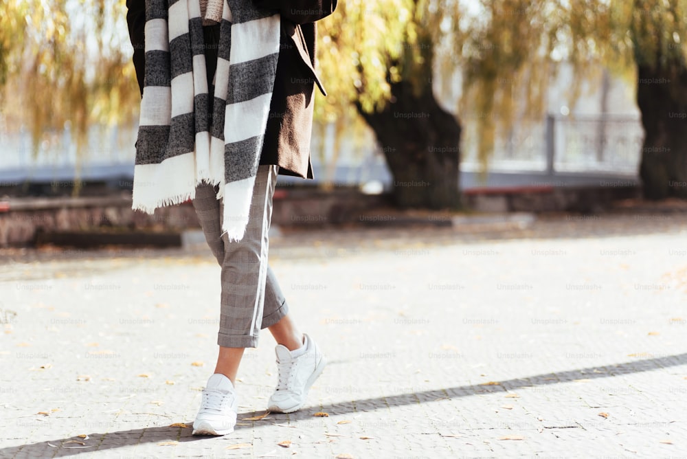 Down part of body. Cropped photo of girl have a walk at sunny autumn day in the park.