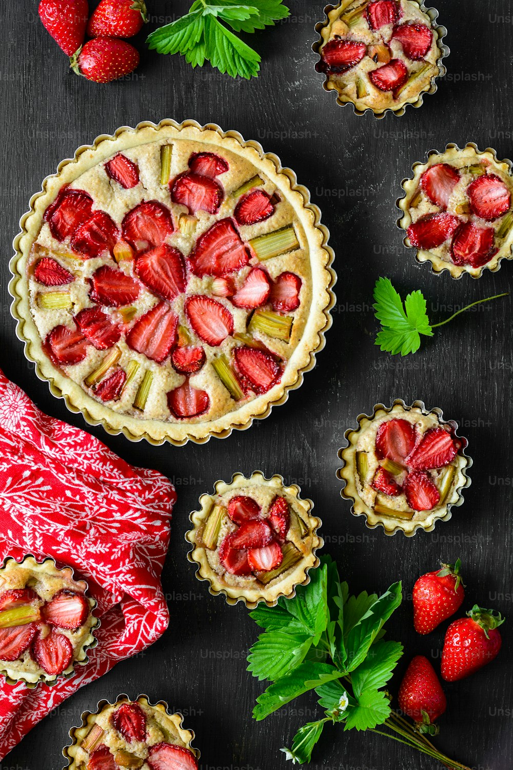 Tartes maison à la fraise et à la rhubarbe sur fond en bois noir. Vue de dessus. Style rustique