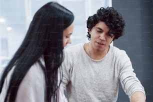 Guy with curly hair talking. Young professionals. Cheerful coworkers in a modern office smiling when doing their job.