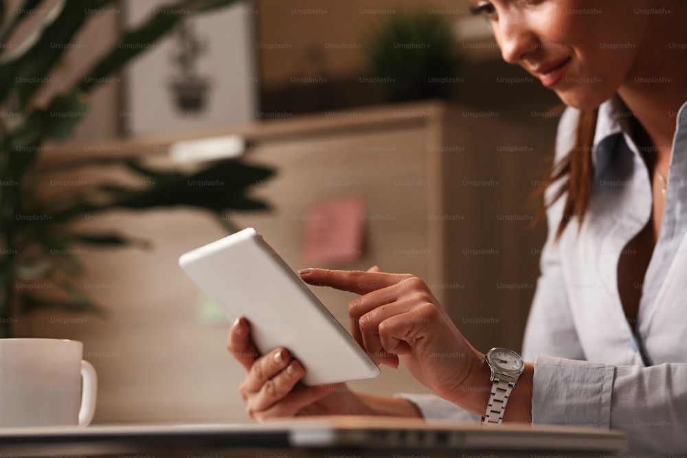 Close up of smiling female manager working on digital tablet in the office.