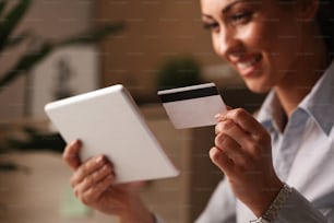 オフィスでタッチパッドとクレジットカードを使用しながらインターネットで購入する幸せなビジネスウーマンのクローズアップ。