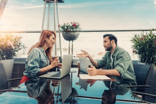 Belle rencontre. Une femme séduisante et un homme barbu discutent du travail dans un café sur le toit