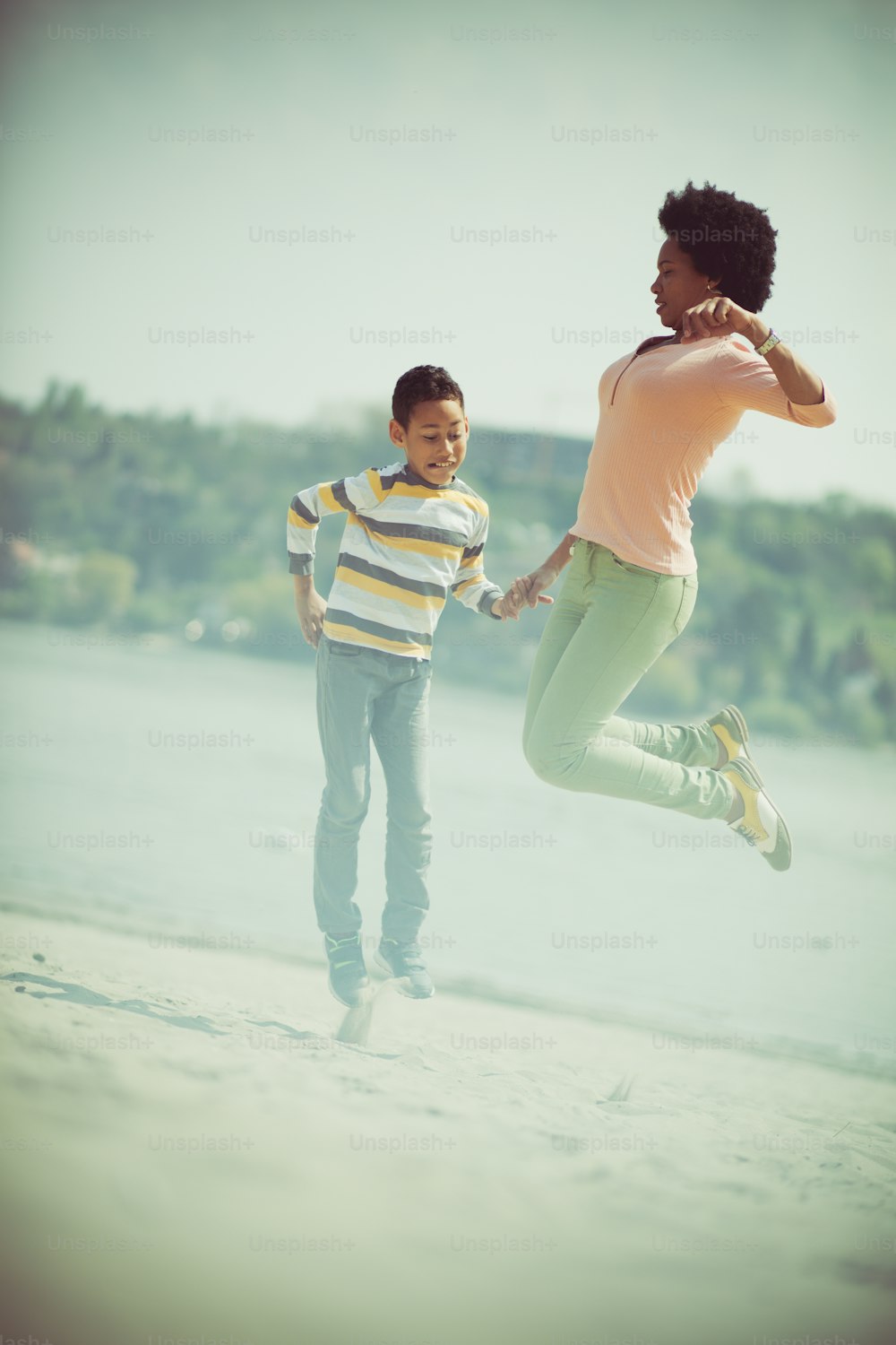 When you're happy, jump high. Mother and son on the beach.