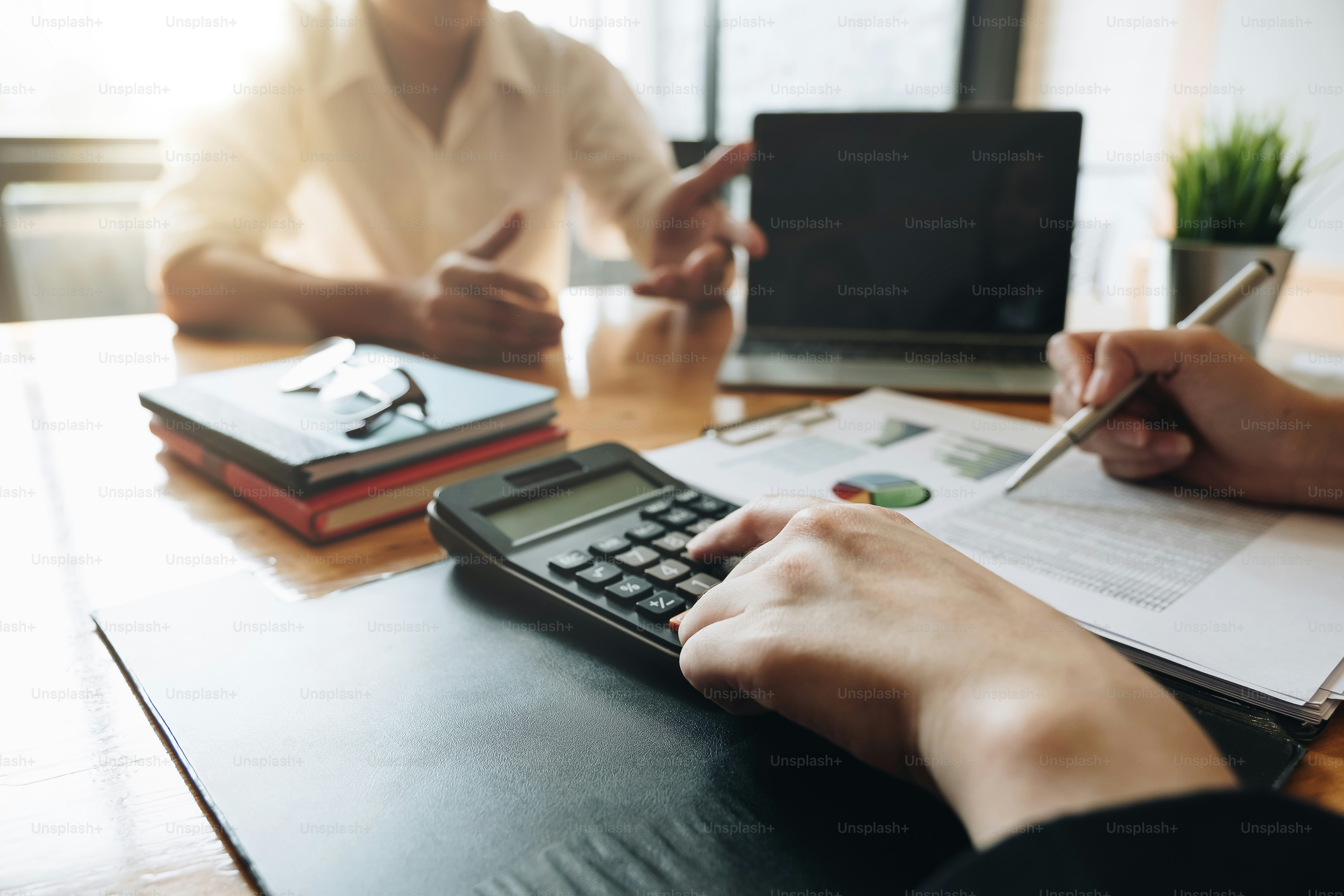 Businesswoman using a calculator and laptop computer to calculate the ...
