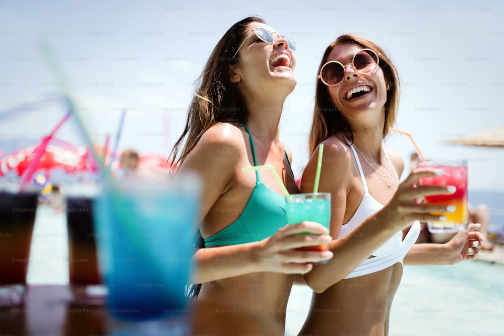 Group of friends having fun on summer vacation and drinking coctails. Youth lifestyle, friendship, travel and holidays concept
