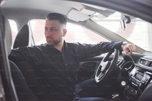 Going back. Side view of man sitting in the modern car with black interior.