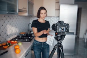 Holding wooden shovel. Girl in the modern kitchen at home at her weekend time in the morning.