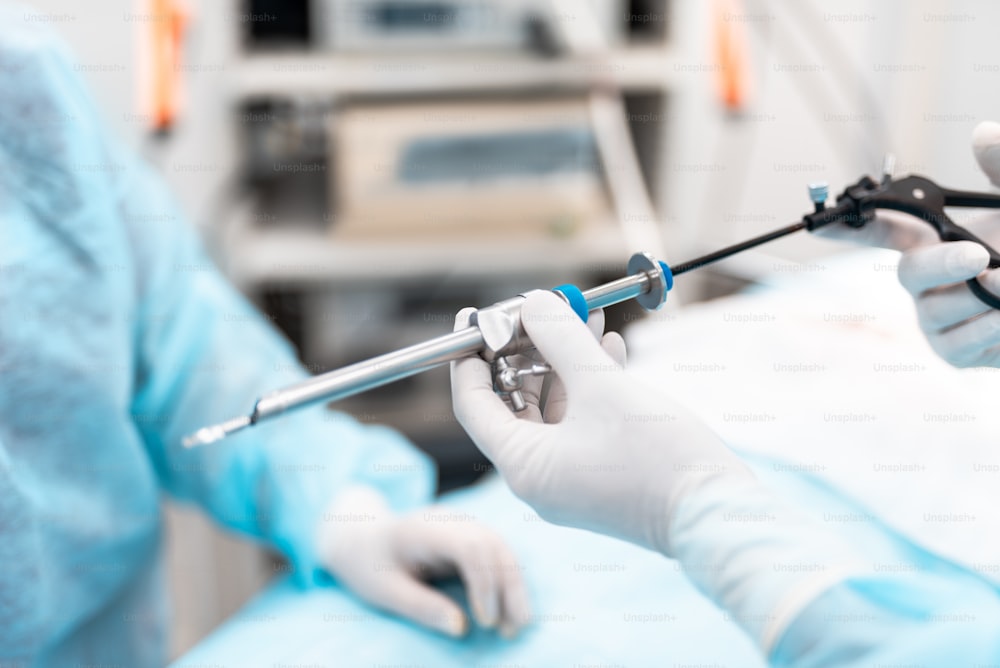 Primer plano de las manos del médico con guantes estériles que unen el trocar laparoscópico a la pinza quirúrgica