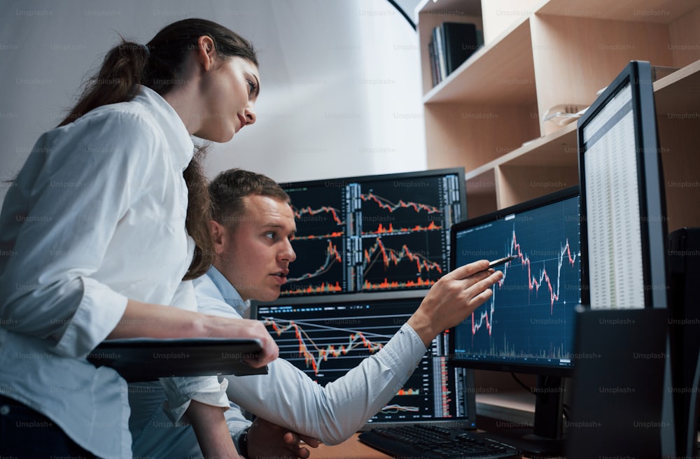 They was have success at that period of time. Team of stockbrokers are having a conversation in a office with multiple display screens.