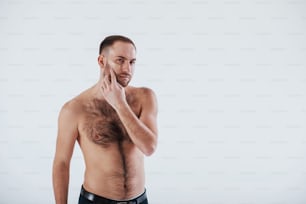 Serious guy at the morning time. Man with bare chest stands against white background in the studio.