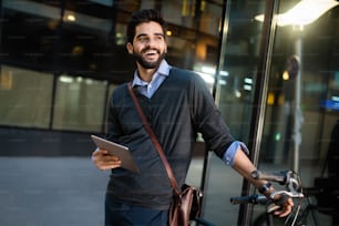 Retrato de hombre de negocios sosteniendo tableta y bicicleta al aire libre