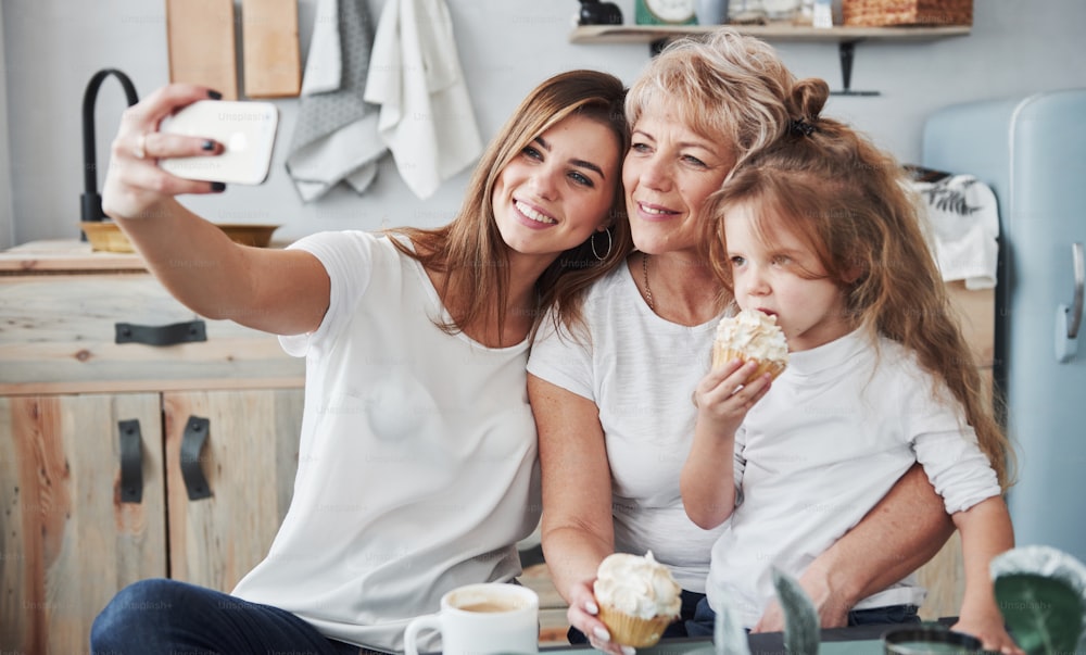 Selfie on smartphone. Mother, grandmother and daughter having good time in the kitchen.