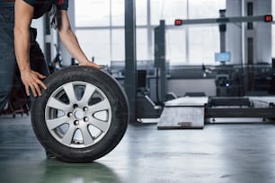 Grounded view. Mechanic holding a tire at the repair garage. Replacement of winter and summer tires.