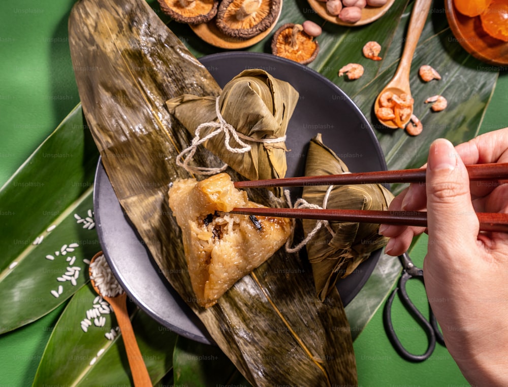 Zongzi, mujer comiendo albóndigas de arroz al vapor sobre fondo de mesa verde, comida en el concepto duanwu del festival del bote del dragón, primer plano, espacio de copia, vista superior, posición plana
